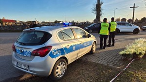 policjanci i radiowóz na drodze w pobliżu cmentarza