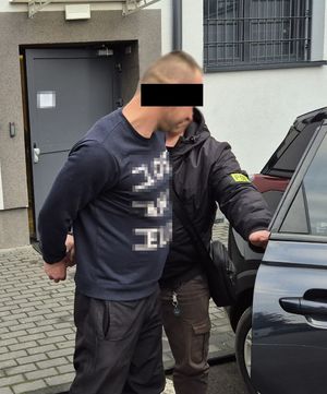 podejrzany o kierowanie gróźb prowadzony do samochodu przez nieumundurowanego policjanta