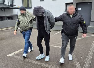 nieumundurowani policjanci prowadzą podejrzanego