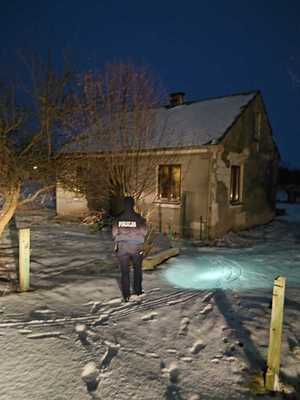 policjantka oświetla otoczenie latarką, w tle budynek mieszkalny