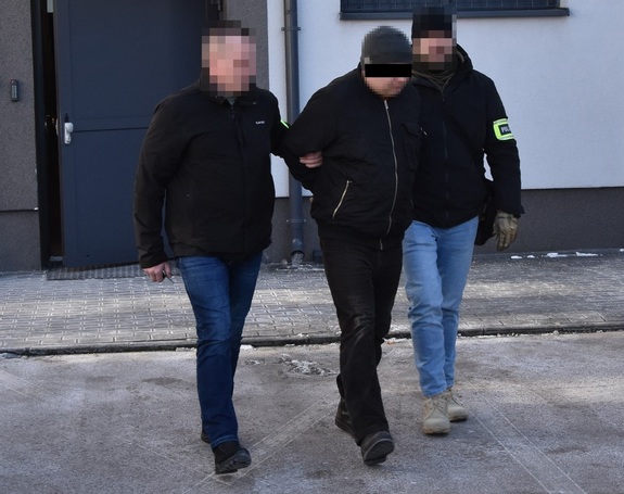 nieumundurowani policjanci prowadzą zatrzymanego