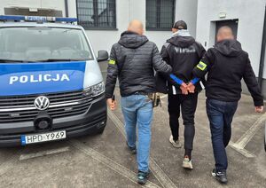 nieumundurowani policjanci prowadzą zatrzymanego mężczyznę w kajdankach
