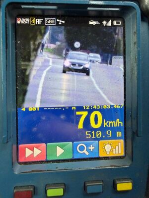 radarowy miernik prędkości z obrazem samochodu jadącego po drodze i wskazaniem jego prędkości