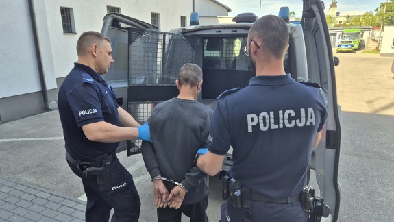 policjanci prowadzą tymczasowo aresztowanego do radiowozu