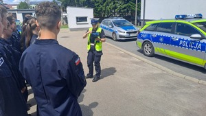 uczniowie i policjantka, w tle radiowozy