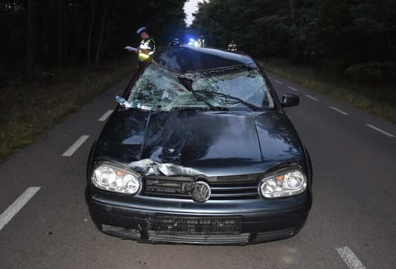 uszkodzony samochód Volkswagen na drodze, obok policjant
