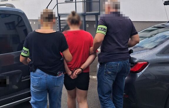 policjanci prowadzą zatrzymana kobietę