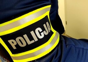 ręka z opaską z napisem Policja