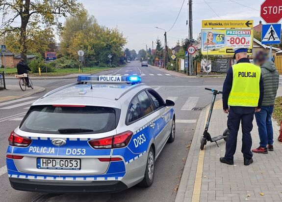 radiowóz, policjant i kierujący hulajnogą na drodze