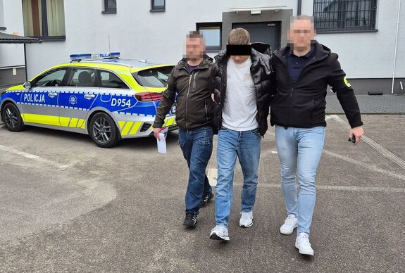 nieumundurowani policjanci prowadzą podejrzanego