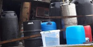 plastikowe beczki i metalowe urządzenie do domowej produkcji alkoholu